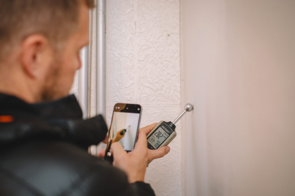 Technický inspektor využívá měříč vlhkosti při inspekci.